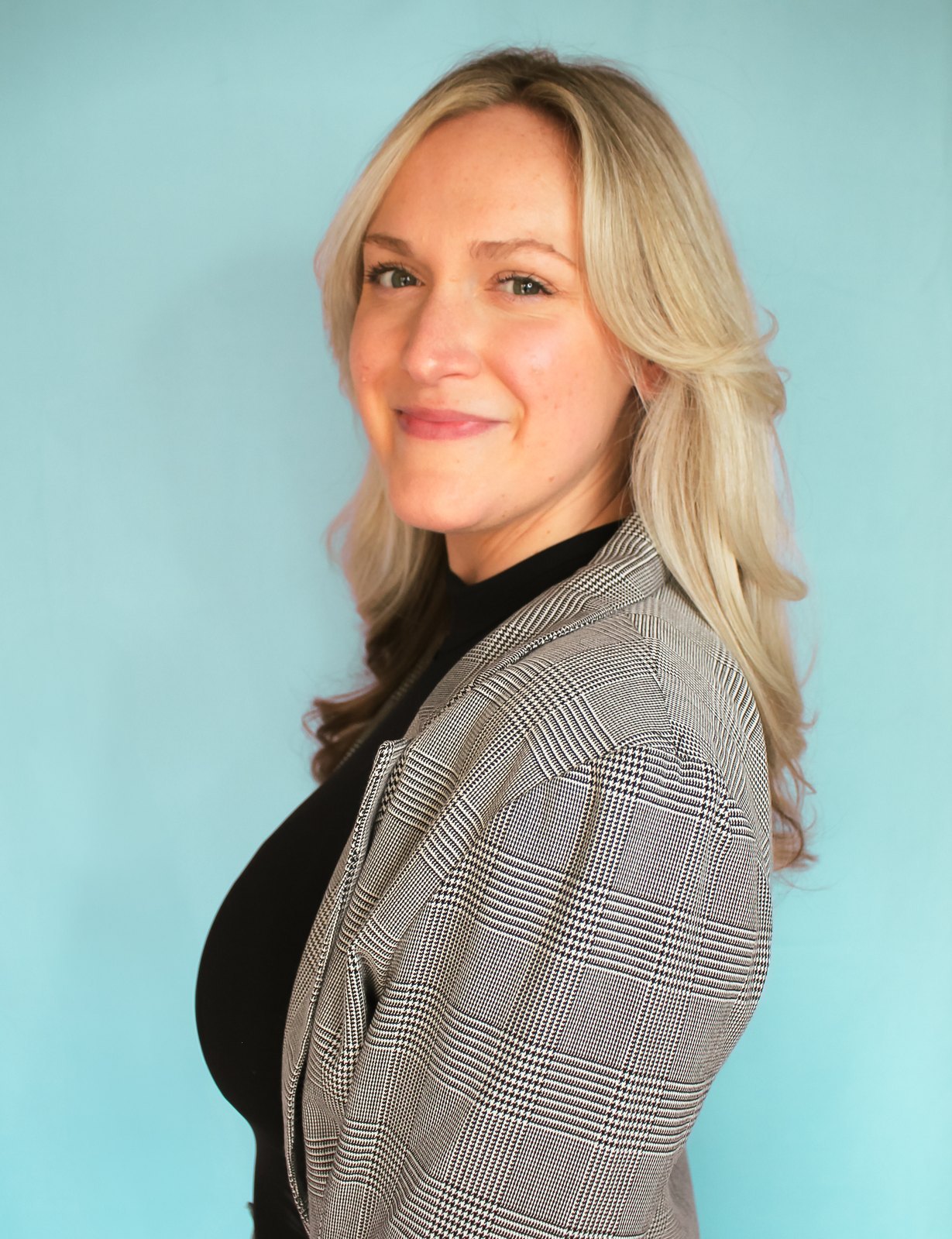 Nicollete Hillegas, HR consultant and career coach, in a grey blazer against a teal backdrop